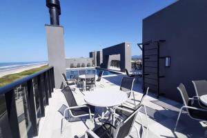 a table and chairs on a balcony with the beach at Studio 105 Maravilhoso Frente Mar Piscina Aquecida in Matinhos