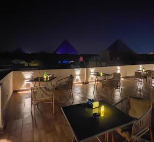 un patio en la azotea con mesas y sillas por la noche en Pyramids Glory INN, en El Cairo