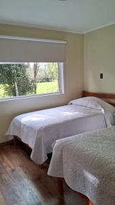 two beds in a bedroom with a window at Cabañas Puerto Varas in Puerto Varas