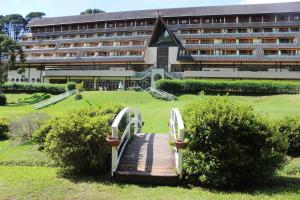 a hotel with a wooden bridge in front of a building at Satélite - Campos do Jordão in Campos do Jordão