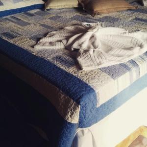 a bed with a blue and white quilt on it at Várzea Palace Hotel in Teresópolis