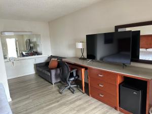 a hotel room with a desk with a television and a bed at Travelodge by Wyndham Parker in Parker