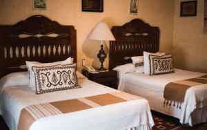 a bedroom with two beds with white and brown pillows at Hacienda El Carmen Hotel & Spa in Portes Gil