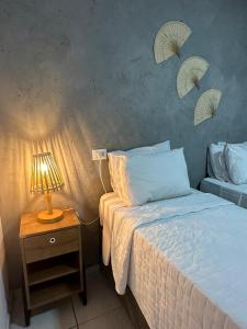 1 dormitorio con 1 cama y 1 mesa con lámpara en Casa Flôr, en Fernando de Noronha