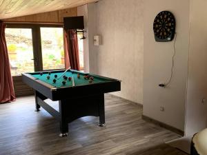 ein Zimmer mit einem Billardtisch in einem Zimmer mit einer Uhr in der Unterkunft Maison de montagne in Auzat