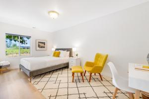 ヒールズバーグにあるVineyard Haven Retreatのベッドルーム1室(ベッド1台、黄色い椅子2脚付)