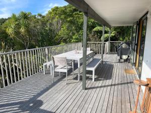 una terraza de madera con mesa y sillas. en Waikawa Bay bach with spectacular views, en Waikawa