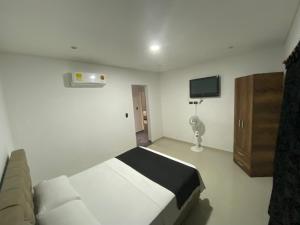 ein Schlafzimmer mit einem Bett, einem TV und einem Sofa in der Unterkunft Hotel Arrendajo in Acacías