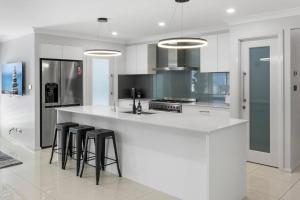 a kitchen with a white counter and black stools at Rengor Executive Retreat in Belmont