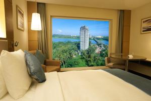 a hotel room with a bed and a large window at Gokulam Grand Trivandrum in Trivandrum