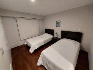 1 dormitorio con 2 camas y una pizarra en la pared en MLA apartments - Bolognesi, en Lima