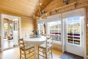 ein Esszimmer mit einem Tisch, Stühlen und einem Fenster in der Unterkunft Gemütliches helles Ferienhaus am See mit Panoramaseeblick + Hütte und nahe Meer in Lyngdal