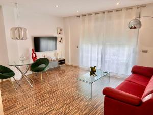 un soggiorno con divano rosso e tavolo in vetro di Apartamento céntrico con plaza de garaje y piscina a Murcia