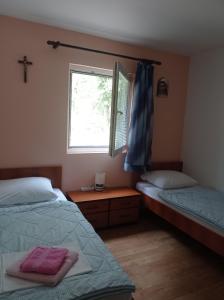 a bedroom with two beds and a window with a cross at Casa Del Pellegrino M&A - Ostojići in Međugorje