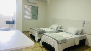 a white room with two beds and a window at Hotel Tenda Diadema in Diadema