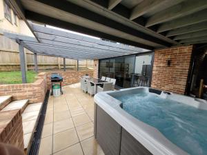 a hot tub in a patio with a table and chairs at Yew Tree Cottage- A beautiful cottage with Hot Tub in Hintlesham