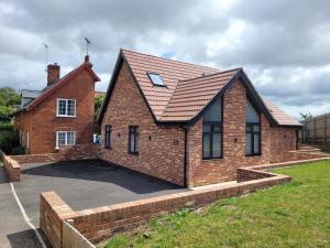 a red brick house with a large driveway at Yew Tree Cottage- A beautiful cottage with Hot Tub in Hintlesham