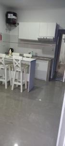 a kitchen with white tables and white stools at Catamarca Apart in Ramallo