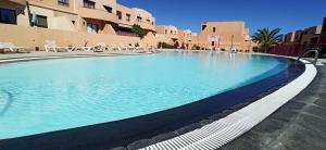 a large swimming pool with blue water in a building at Bahia Sol Dream -Caleta de Fuste- in Caleta De Fuste