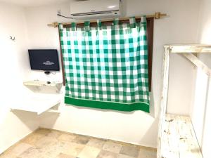 ein Bad mit einem grünen und weißen, karierten Duschvorhang in der Unterkunft Maria Flor Pousada in Taíba