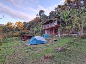 une tente dans un champ en face d'une maison dans l'établissement Solar Picu Eco-hospedaria, à Itamonte
