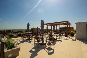 un patio con mesas y sillas en la azotea en Bela Hospedagem - EcoSummer Flats em Tambaú, en João Pessoa