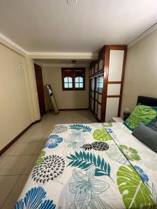 - une chambre dotée d'un lit avec un couvre-lit floral dans l'établissement Le Cocotier, à Lamentin