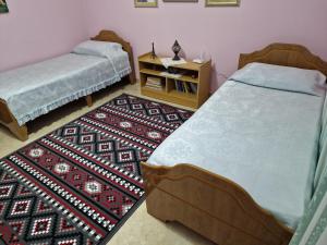 a bedroom with two beds and a rug at vila dhimo in Fier