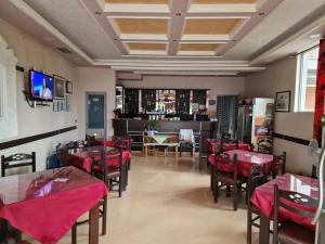a restaurant with red tables and chairs and a tv at vila dhimo in Fier