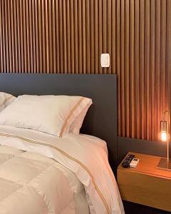 格拉馬杜的住宿－Austin Suites Gramado，一间卧室配有一张床和一张带台灯的桌子