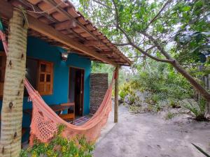 a blue house with a hammock in front of it at Pousada Flor do Xandó Caraíva in Caraíva