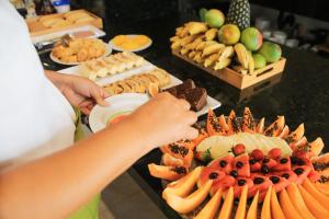 a person reaching for a plate of fruit on a buffet at Hotel Icaraí Beach in Icaraí