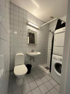 a bathroom with a toilet and a sink and a washing machine at The swiss suites in Oslo