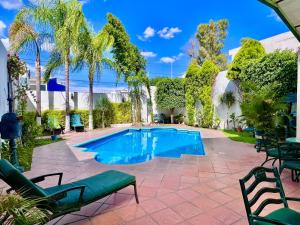 una piscina en un patio con sillas y árboles en Hotel Florencia by Marho, en Querétaro
