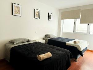 a bedroom with two beds with black blankets and a window at Zona Exclusiva Céntrico 7 pers. Cochera in Arequipa