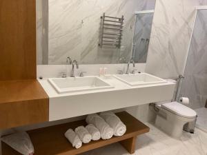 Baño blanco con lavabo y aseo en Austin Suites Gramado, en Gramado