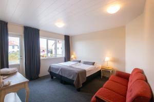 a hotel room with a bed and a red couch at DalsSel farm Guesthouse in Hólmabæir