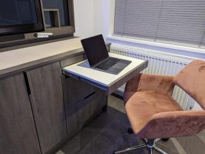 Claresholm في بارنيت: يوجد جهاز كمبيوتر محمول على مكتب مع كرسي
