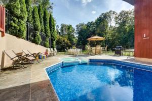 a swimming pool in a yard with chairs and an umbrella at Spacious Woodbury Home with Pool and Hot Tub! in Woodbury