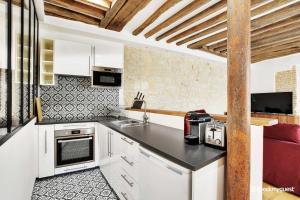 a kitchen with white cabinets and a black counter top at Amazing Apartment 2BR6P - St Lazare South Pigalle in Paris