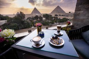 a table with two cups of coffee and a plate of food at PANORAMA view pyramids in Cairo