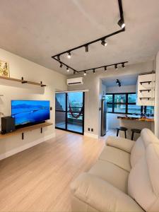 un soggiorno con divano e TV a schermo piatto di PALMAS EXPERIENCE - Apartamento Girassol a Palmas