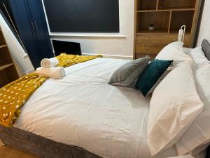 a large white bed with pillows on top of it at De Luxe Apartment in Leicester