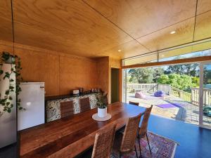 a kitchen with a wooden table and a refrigerator at Tui Nature Retreat in Hotwater Beach