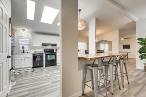 a kitchen with white cabinets and a bar with stools at Phoenix Family Home Near Cave Creek and Hiking! in Phoenix