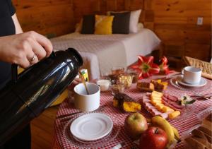 a person is pouring coffee into a table with food at Estalagem Refúgio do Capão in Cambará