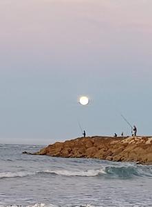 a group of people fishing on the shore of the ocean at Caparica Apartment near beach in Costa da Caparica