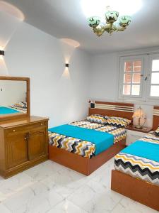 a bedroom with two beds and a mirror and a dresser at فيلا مارينا 4 الساحل الشمالي in El Alamein