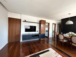 uma sala de estar com uma mesa de jantar e uma televisão em Apartamento em Belo Horizonte 2 em Belo Horizonte