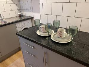 a kitchen counter with two plates and wine glasses at De Luxe Apartment in Leicester